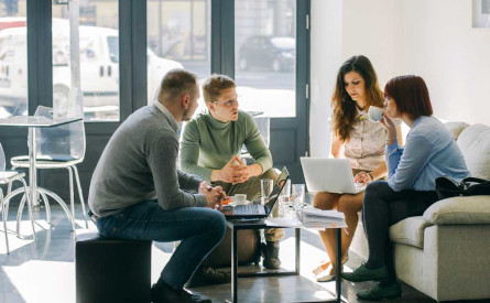 Photo of four people working at a coffee table